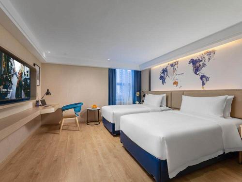 a hotel room with two beds and a tv at Kyriad Marvelous Hotel Shenzhen Nanlian Metro Station in Longgang