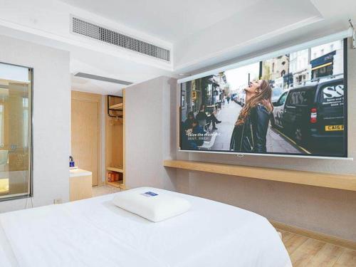 a room with a bed and a tv on a wall at Kyriad Marvelous Hotel Dongguan Changan Light Rail Station in Nongyucun