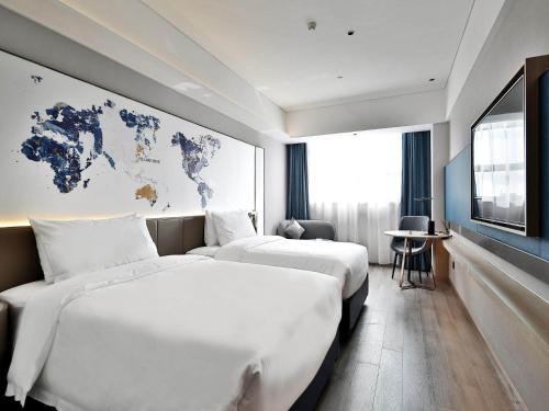 南昌的住宿－凯里亚德酒店(南昌象湖金沙大道店)，两张位于酒店客房的床,墙上有地图
