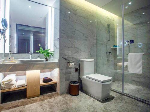 uma casa de banho com um chuveiro, um WC e um lavatório. em Kyriad Marvelous Hotel Fujian Xiapu Railway Station em Xiapu