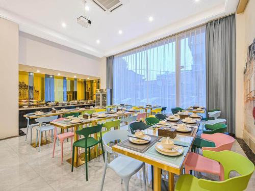 a restaurant with tables and chairs and a large window at Vienna Classic Hotel Wenzhou Cangnan High-Speed Railway Station Shop in Cangnan