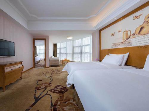 a hotel room with two beds and a flat screen tv at Vienna International Hotel ASEAN Avenue Dongxing in Fangcheng