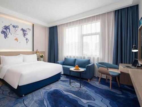 Habitación de hotel con cama y sofá azul en Kyriad Marvelous Hotel Shenzhen Baoan Gushu Metro Station, en Bao'an