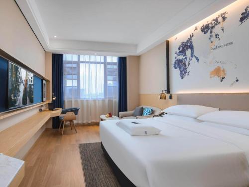 Kyriad Marvelous Hotel Bozhou Wanda Plaza في Bozhou: غرفة فندقية بسريرين كبار وتلفزيون