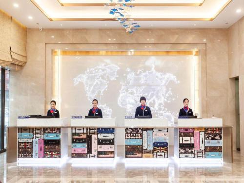 a group of men standing behind a counter with a map at Kyriad Marvelous Hotel Weihai Railway Station in Weihai