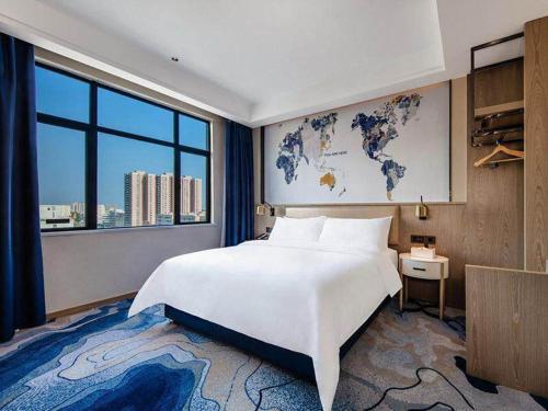 Un dormitorio con una gran cama blanca y una gran ventana. en Kyriad Marvelous Hotel Haifeng, en Haifeng