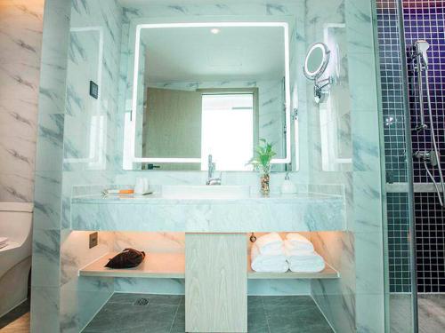 a bathroom with a sink and a mirror at Kyriad Marvelous Hotel Foshan Xiqiao Mountain Scenic Area Qiaoling Square in Nanhai