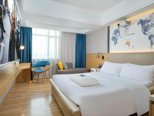 Habitación de hotel con cama blanca grande y escritorio. en Kyriad Marvelous Hotel Dongguan Changan Light Rail Station en Nongyucun
