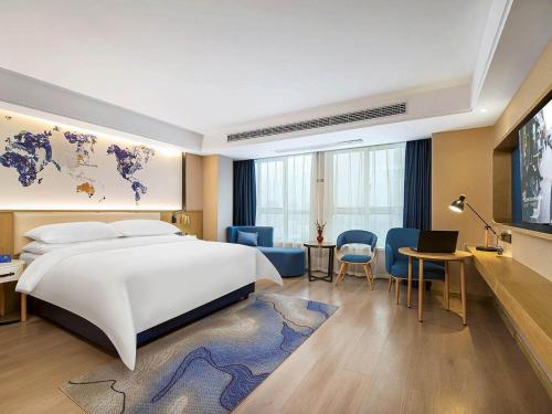 XinyangにあるKyriad Marvelous Hotel Henan Xinyang Pingqiao Plazaのベッドルーム1室(大型ベッド1台、ノートパソコン付きのデスク付)