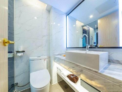 a bathroom with a sink and a toilet and a mirror at Kyriad Marvelous Hotel Changsha Xiangya in Changsha