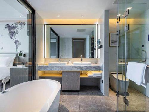Un baño con bañera, lavabo y ducha. en Kyriad Marvelous Hotel Haifeng, en Haifeng