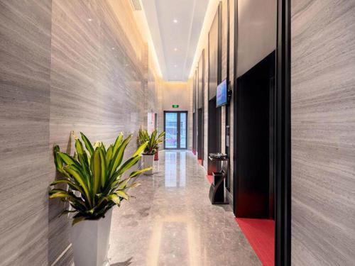 a hallway with potted plants in a building at Kyriad Marvelous Hotel Guizhou Dujun Center Wanda Plaza in Duyun