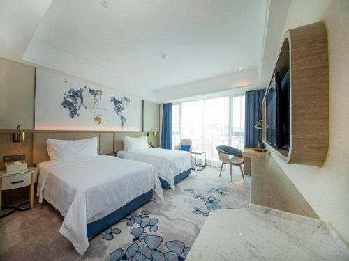 a hotel room with two beds and a television at Kyriad Marvelous Hotel Foshan Xiqiao Mountain Scenic Area Qiaoling Square in Nanhai
