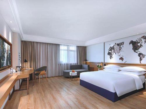 a hotel room with a large bed and a desk at Kyriad Marvelous Hotel Shanghai Daning International Plaza in Shanghai