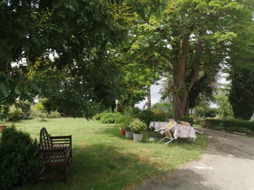 un parc avec deux bancs, une table et des arbres dans l'établissement Comme chez vous "pour 4 personnes", à Puycornet