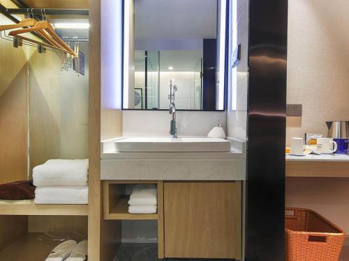a bathroom with a sink and a mirror and towels at Kyriad Marvelous Hotel Henan Xinyang Pingqiao Plaza in Xinyang