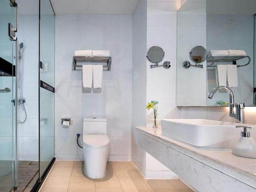 a bathroom with a toilet and a sink and a shower at Kyriad Marvelous Hotel Shenzhen North Railway Station Yousong in Tiantangwei