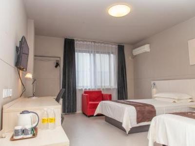 a hotel room with two beds and a red chair at Jinjiang Inn Jurong Renmin Road Gexianhu Park in Jurong