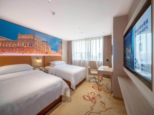 a hotel room with two beds and a flat screen tv at Vienna Hotel Qingyuan City Square Lianjiang Road Hotel in Qingyuan