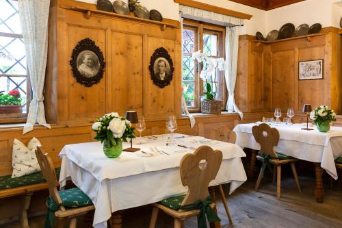 a dining room with two tables with white tablecloths at Romantik Hotel Oberwirt in Marlengo