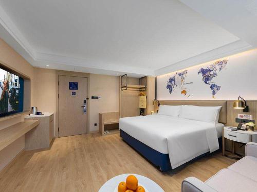a hotel room with a large bed and a couch at Kyriad Marvelous Hotel Shenzhen Nanlian Metro Station in Longgang