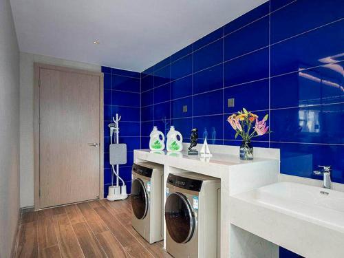 洛陽的住宿－凯里亚德酒店(洛阳龙门高铁站店)，蓝色的浴室设有洗衣机和水槽