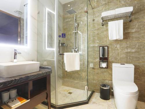 a bathroom with a toilet and a sink and a shower at Kyriad Marvelous Hotel Harbin Railway Station Central Avenue in Harbin