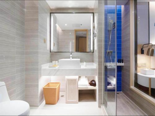 a bathroom with a sink and a mirror at Kyriad Hotel Shenzhen Pingdi Low Carbon City in Longgang