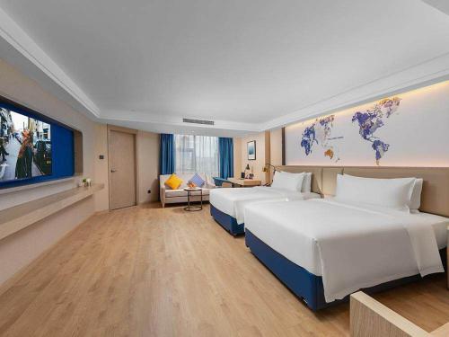 a hotel room with two beds and a flat screen tv at Kyriad Marvelous Hotel Shenzhen Nanlian Metro Station in Longgang