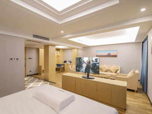 Kailyad Hotel Jiujiang Duchang Pedestrian Street في Duchang: غرفة بسرير وصالة