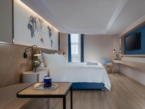 a hotel room with a bed and a table at Kyriad Marvelous Hotel Huizhou South Station Danshui YI Center in Huizhou