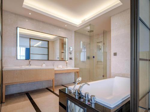 a bathroom with a tub and a sink and a bath tub at Kyriad Marvelous Hotel Dongguan Municipal Government in Dongguan