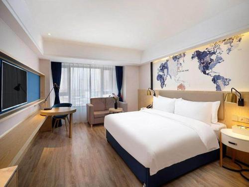 um quarto de hotel com uma grande cama branca e um sofá em Kyriad Marvelous Hotel Haerbin West High-Speed Railway Station Wanda em Harbin