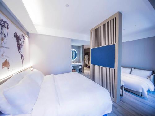 a bedroom with a large white bed and a couch at Kyriad Marvelous Hotel Qinhuangdao Nandaihe in Qinhuangdao