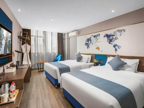 a hotel room with two beds and a tv at Kyriad Marvelous Hotel Wuxi Zhongshan Road Chong'an Temple in Wuxi