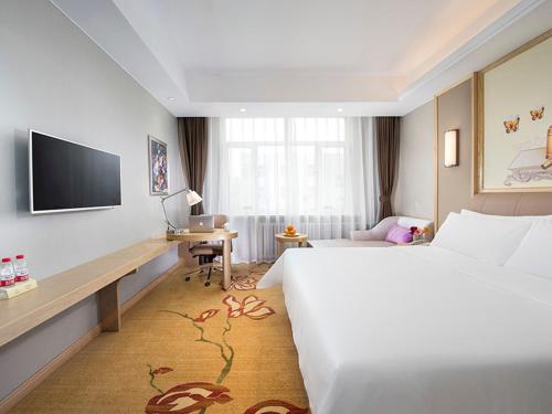 Cette chambre comprend un grand lit et un bureau. dans l'établissement Vienna International Hotel Mongolia Chifeng High-Speed Railway Station, à Chifeng