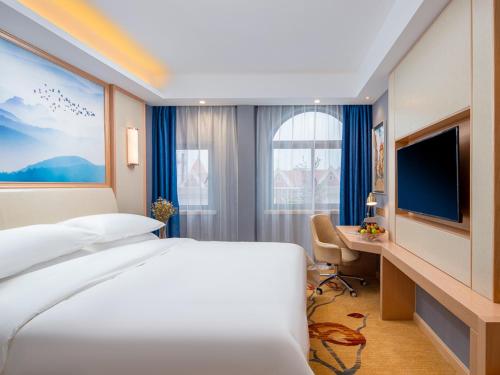 a bedroom with a bed and a desk and a television at Vienna Hotel Lukou Airport in Jurong