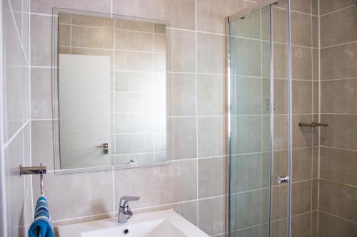 a bathroom with a sink and a shower with a mirror at 1368 The Blyde Crystal Clear 1 Bedroom Apartment in Pretoria