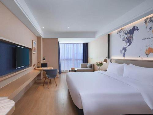 um quarto de hotel com uma grande cama branca e uma televisão em Kyriad Marvelous Hotel Suzhou Wujiang People Square em Suzhou