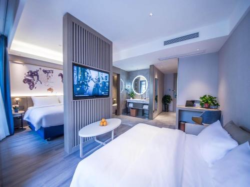 a hotel room with a bed and a tv at Kyriad Marvelous Hotel Qinhuangdao Nandaihe in Qinhuangdao