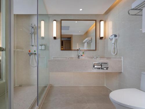 een badkamer met een douche, een wastafel en een toilet bij Vienna International Hotel South Gate of Shenzhen International Convention and Exhibition Center in Bao'an