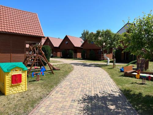 a childs play area with a playground and a house at Ala i Tomek domki in Łeba
