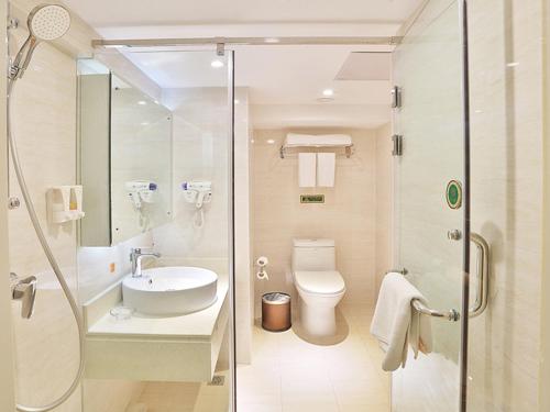 La salle de bains est pourvue de toilettes, d'un lavabo et d'une douche. dans l'établissement Vienna Hotel Harbin West Railway Station Wanda Plaza, à Harbin