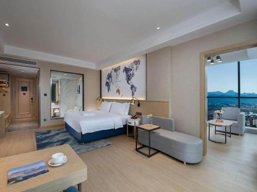 a hotel room with a bed and a living room at Kyriad Marvelous Hotel Guilin Quanzhou in Quanzhou