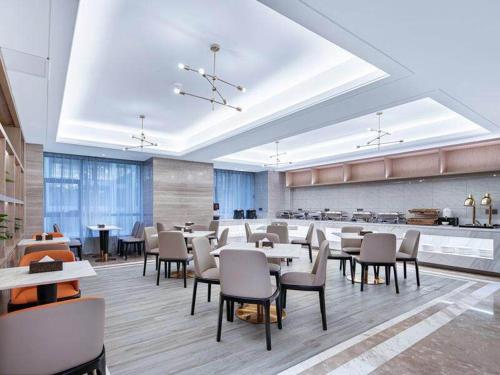 a restaurant with tables and chairs in a room at Kyriad Marvelous Hotel Guizhou Dujun Center Wanda Plaza in Duyun