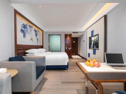 Cette chambre comprend un lit et un bureau avec un ordinateur portable. dans l'établissement Kyriad Hotel Shantou Chaoyang Heping store, à Chaoyang