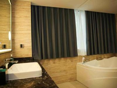 a bathroom with a sink and a toilet and a tub at Magnolia Business Hotel Yangzhou Wanda Plaza Shunda Road in Yangzhou