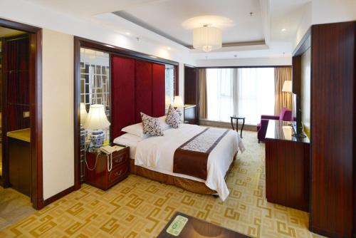 um quarto de hotel com uma cama grande e uma televisão em Vienna International Hotel Yangzhou Wanda Lippo Plaza em Yangzhou
