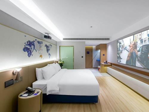 pokój hotelowy z dużym łóżkiem i telewizorem w obiekcie Kyriad Hotel Jiujiang Happy City w mieście Jiujiang