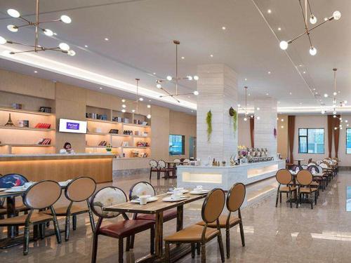 ein Restaurant mit Tischen und Stühlen und eine Bar in der Unterkunft Kyriad Marvelous Hotel Dongguan Huangjiang Jingyi in Dongguan